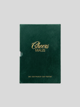 Dunkelgrüner, samtiger Buchschuber des Cocktailbuchs „Cheers Maus“ mit goldener Prägeschrift und dem Untertitel „Das Cocktailbuch zum Podcast“ auf grauem Hintergrund.