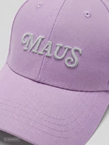 Detailansicht einer fliederfarbenen Cap aus Baumwoll-Twill mit gebogenem Schirm. Zu sehen ist der gestickte „MAUS“-Schriftzug in Weiß auf der Vorderseite sowie die Struktur des Materials und der Stickerei.