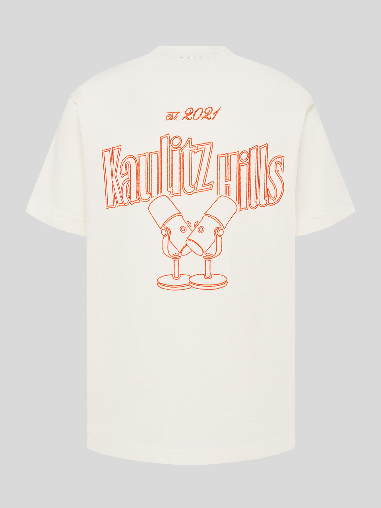 Weißes T-Shirt mit großem orangefarbenem Rückenstick „Kaulitz Hills est. 2021“ und Illustration von zwei Mikrofonen.