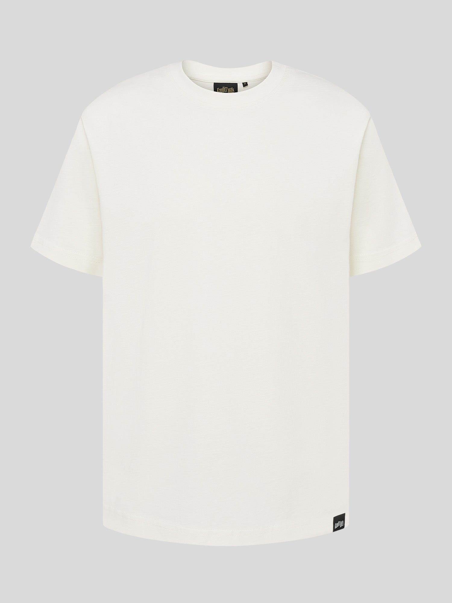 Weißes T-Shirt mit schlichtem Design und kleinem schwarzen Label „Kaulitz Hills“ am unteren Bund.